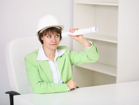 The woman - a builder in a helmet with a drawing in the hands