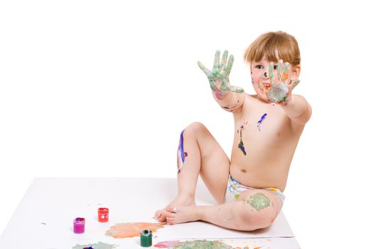 a girl with dirty face and hands of color paint seat on the floor and show her hands