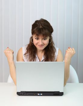 A young girl is happy looking at the computer screen