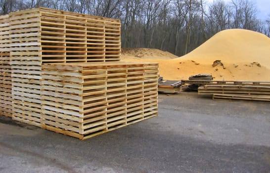 new wood pallets outside pallet plant next to pile of waste sawdust, waiting to be delivered