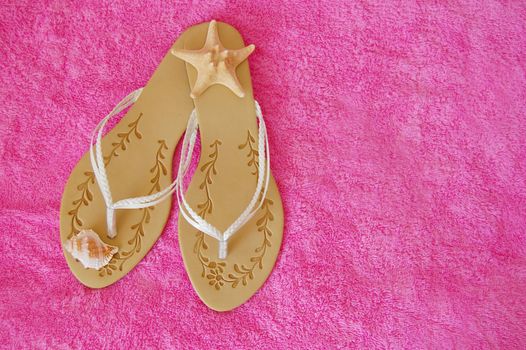 beach sandals with seashells on pink towel
