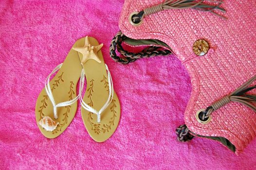 beach sandals with seashells, bag on pink towel