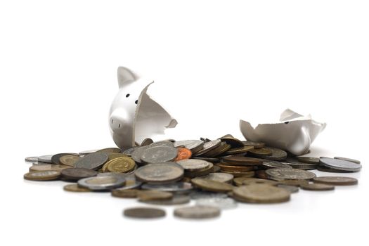 A broken piggy bank isolated on a white background with loads of coins from around the world.