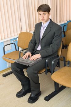 The person in a suit with the laptop in a lap