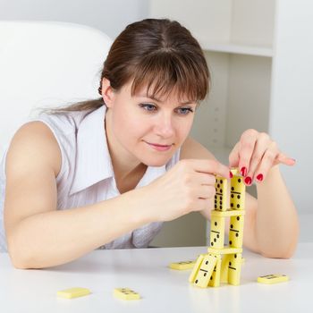 Funny woman are concentrated in building a tower on the table with the domino