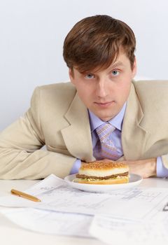 A young man in a light jacket and a big sandwich