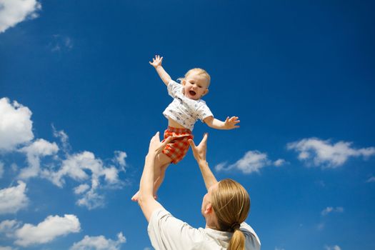 father throw his daughter over blue sky