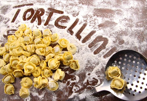 Fresh, raw tortellini with flour and kitchen utensil