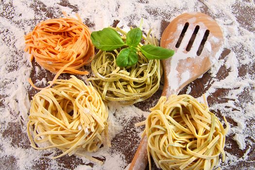 Uncooked italian pasta in three colours with flour