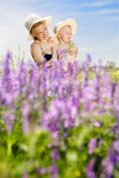 mother and small daughter on the sunny field of wild vetch