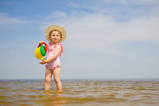 small girl with watering-pot on the seashore