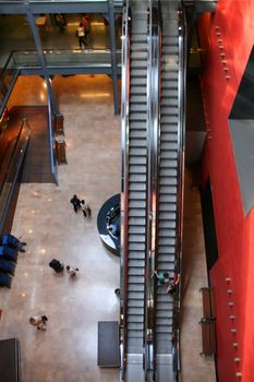 indoors view of a mall, escalators, consumers, lobby.