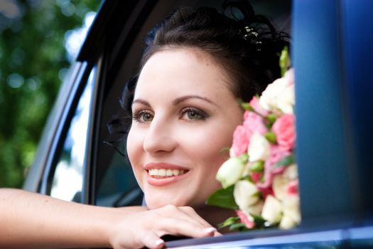 beautiful bride with flowers in the car