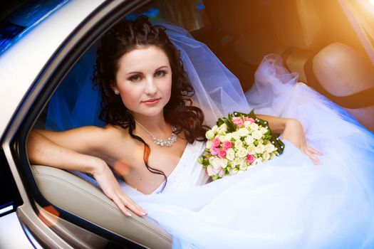 beautiful bride with flowers in the car