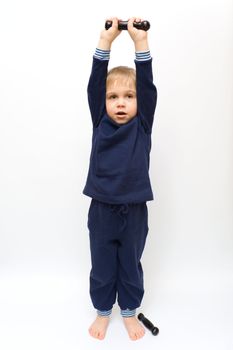 The boy carries out exercises with dumbbells
