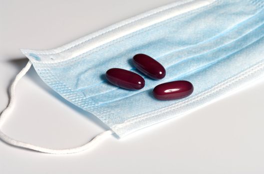 Three red capsule at a medical mask.