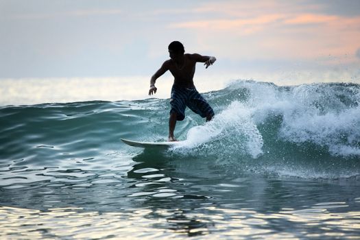 Surfer in ocean on sunset. Bali. Indonesia