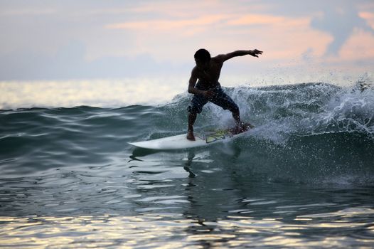 Surfer in ocean on sunset. Bali. Indonesia