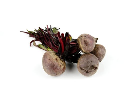 A bunch of raw red beetroot on a reflective white background