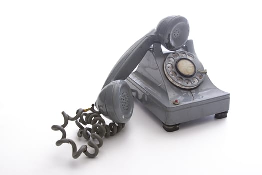 dirty vintage gray unhooked rotary phone with crack casing and expose wired