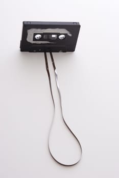 old tape cassette with cover sticker rip apart and part of the tape unrolled