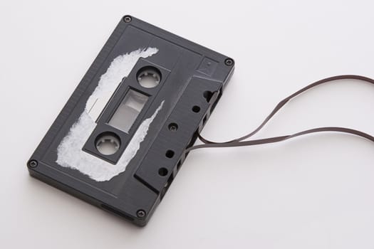 old tape cassette with cover sticker rip apart and part of the tape unrolled