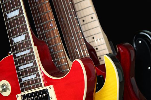 Closeup of four electric guitars isolated over a black background.