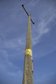 Power line with a danger sign and clear blue sky.