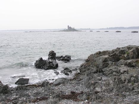 Waves crash over black rocks on a Maine Beach