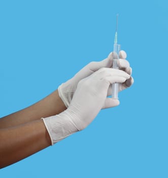 Close-up image of two hands in gloves preparing an injectable solution in a syringe.