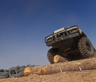 Off road car passing a tree trunk obstacle during a competition.