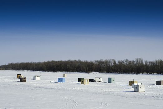 Scattered shacks used for ice fishing situated on the frozen "Red River" in Manitoba.