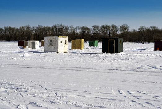 Scattered shacks used for ice fishing situated on the frozen "Red River" in Manitoba.