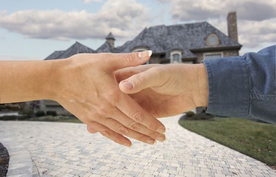 Man and woman shaking hands in front of a new house with clipping path.