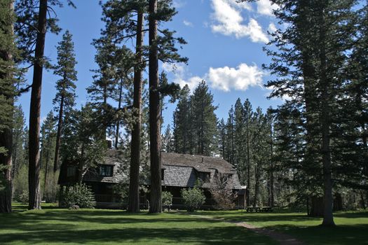 Beautiful mountain lake-front vintage cottage with grass and trees.
