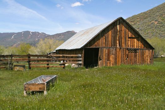 Taken in the Sierras - a rustic, old, abandoned barn rich with old wood and overgrown grass.