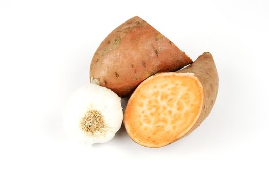 Sweet Potato cut in half with a white garlic bulb on a reflective white background