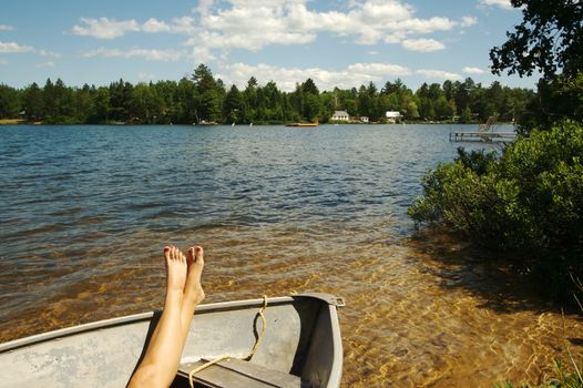 Lake scene of a woman relaxing in a row boat during a summer day.