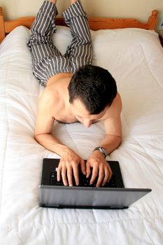 man on working on laptop in bed