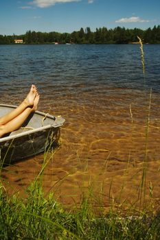 Lake scene of a woman relaxing in a row boat during a summer day.