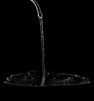 Tap with splashing water on black background