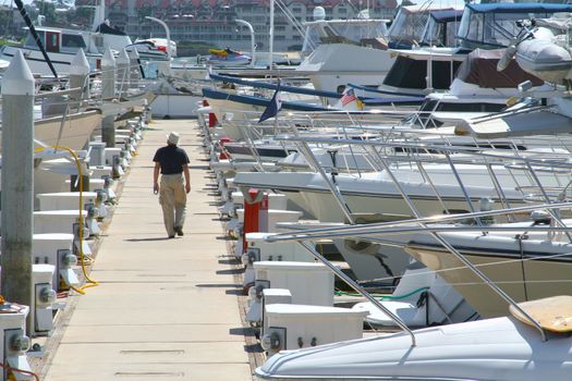 A gentleman takes a walk down the dock.