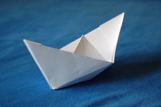 origami paper boat isolated on blue water