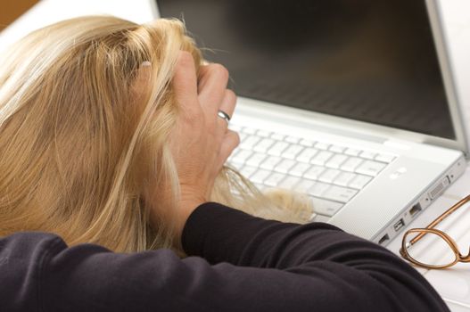 Female hold her head in frustration  while using her laptop.