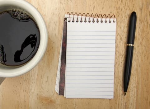 Note Pad Coffee Cup and Pen on Wood Background