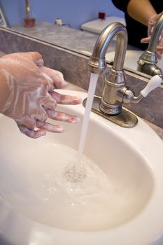 A person washing their hands in the bathroom sink
