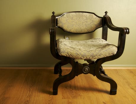 Roman Styled Chair Against an Olive Green Wall