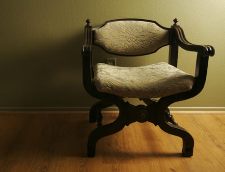 Roman Styled Chair Against an Olive Green Wall