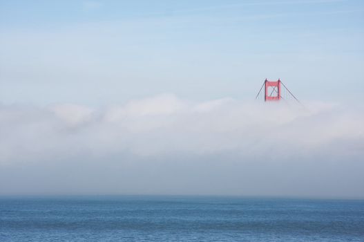 A Golden Gate Bridge tower peaks out of the early morning fog. San Francisco, California, United States.