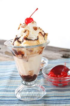 A hot fudge sundae with toppings and a white background.